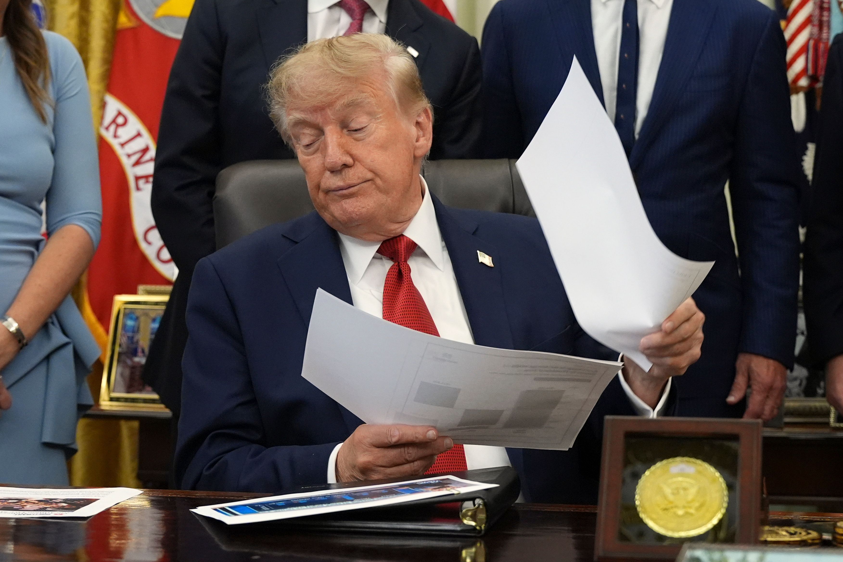 Donald Trump hält Dokumente in der Hand, während er im Oval Office des Weißen Hauses über das Gesundheitswesen spricht.