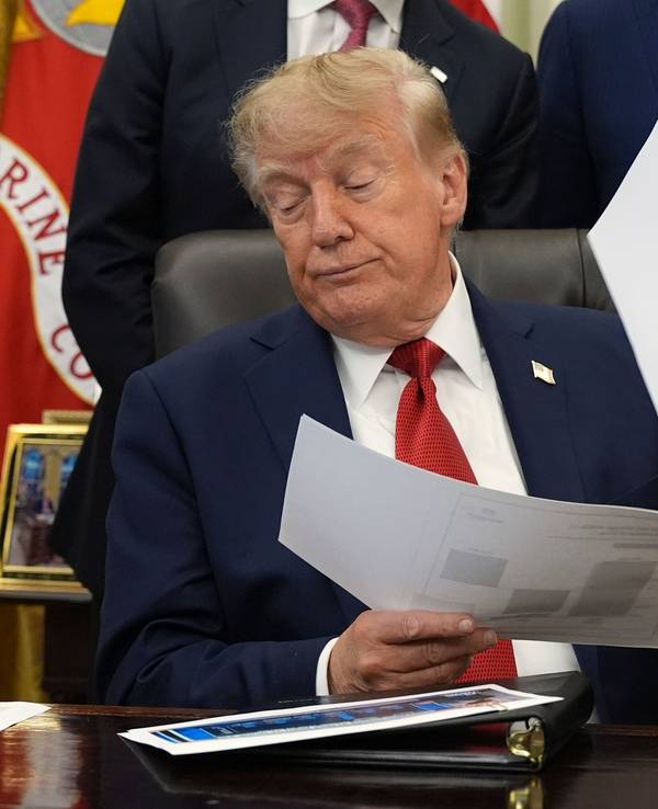 Donald Trump hält Dokumente in der Hand, während er im Oval Office des Weißen Hauses über das Gesundheitswesen spricht.