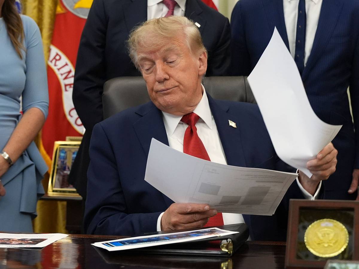 Donald Trump hält Dokumente in der Hand, während er im Oval Office des Weißen Hauses über das Gesundheitswesen spricht.