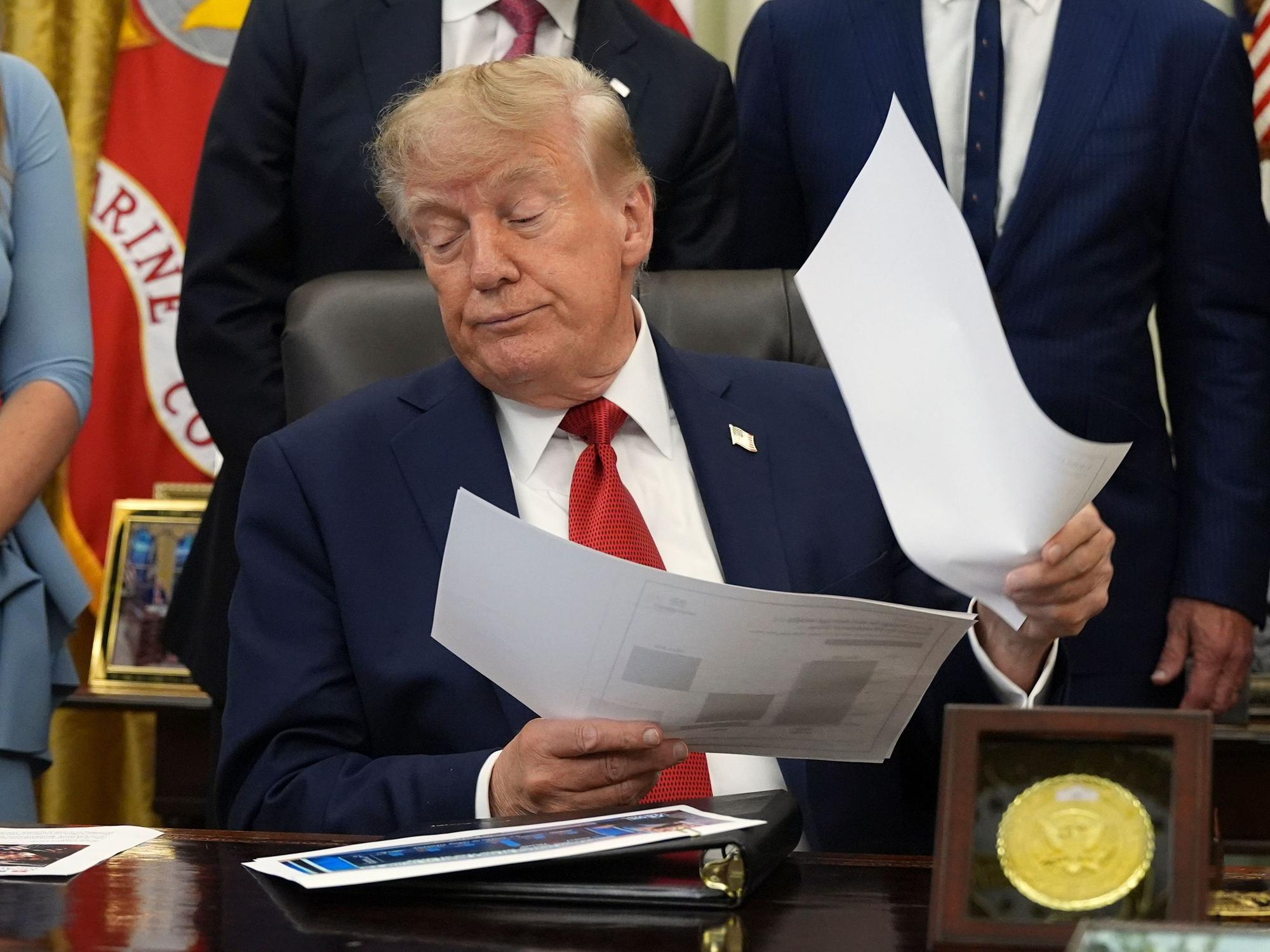 Donald Trump hält Dokumente in der Hand, während er im Oval Office des Weißen Hauses über das Gesundheitswesen spricht.