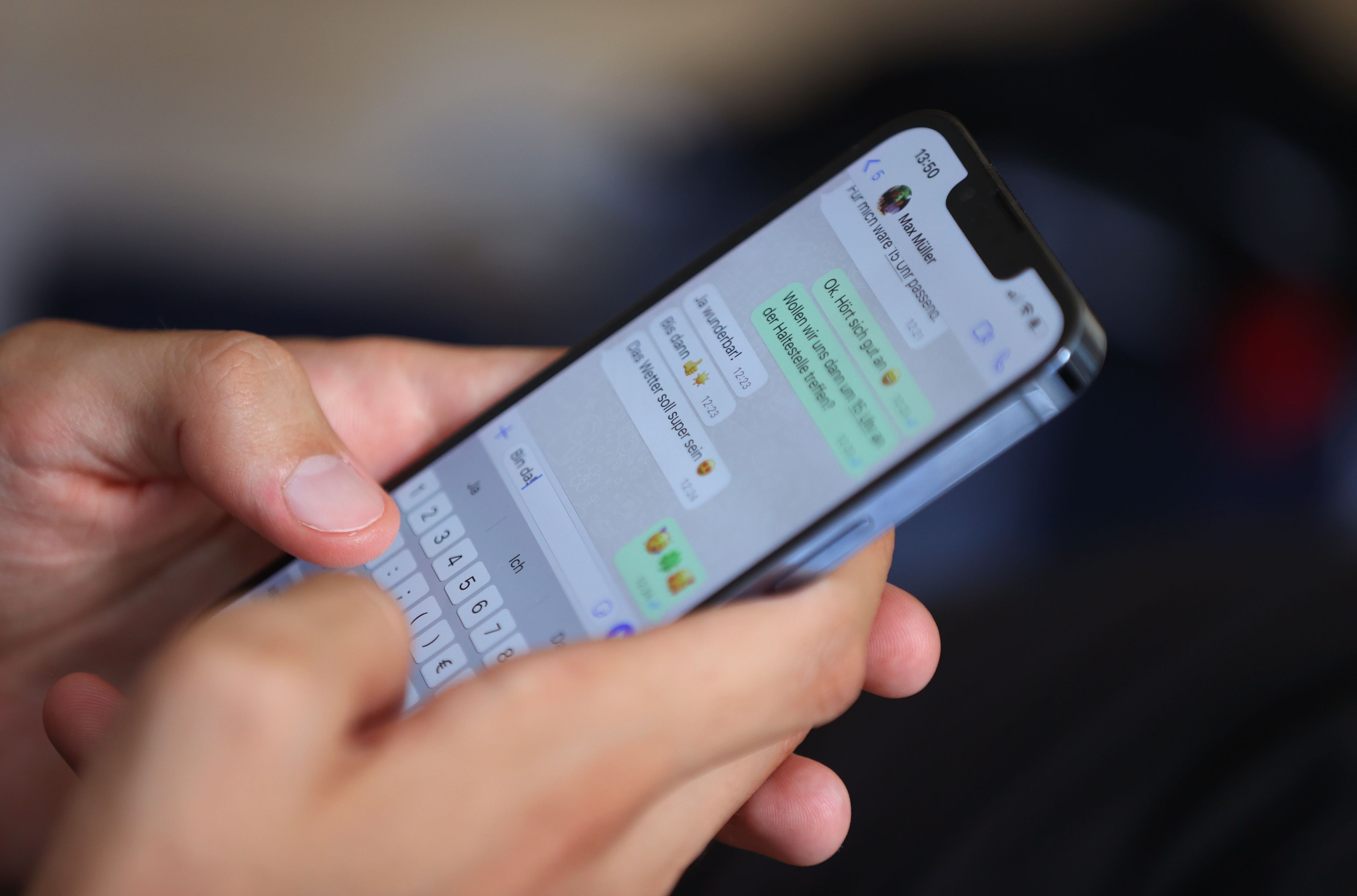 Ein junger Mann tippt auf einem Smartphone eine WhatsApp-Nachricht.