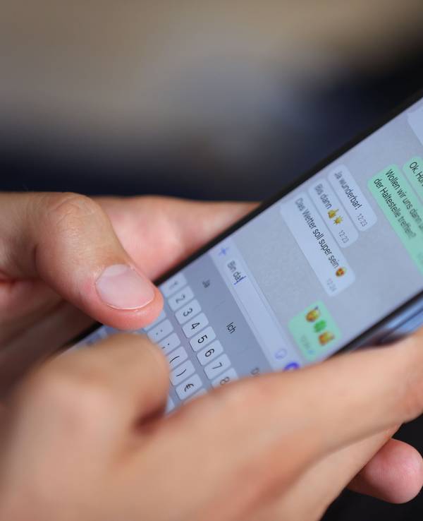 Ein junger Mann tippt auf einem Smartphone eine WhatsApp-Nachricht.