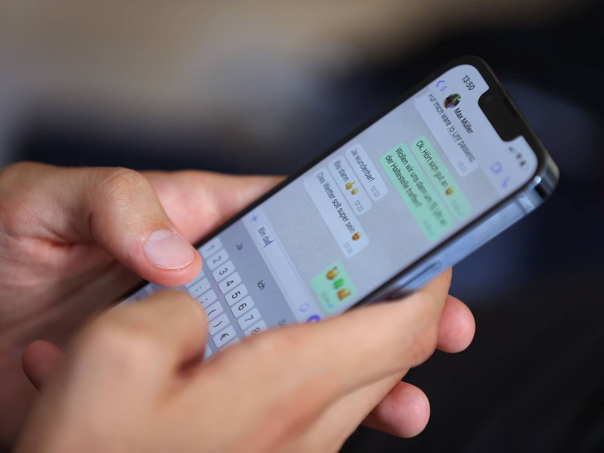 Ein junger Mann tippt auf einem Smartphone eine WhatsApp-Nachricht.