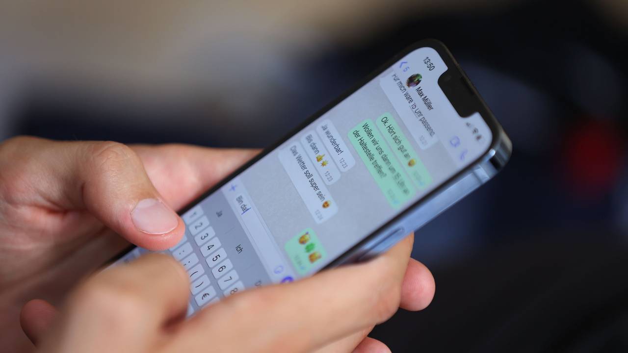 Ein junger Mann tippt auf einem Smartphone eine WhatsApp-Nachricht.