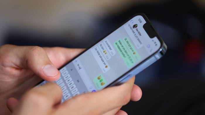 Ein junger Mann tippt auf einem Smartphone eine WhatsApp-Nachricht.