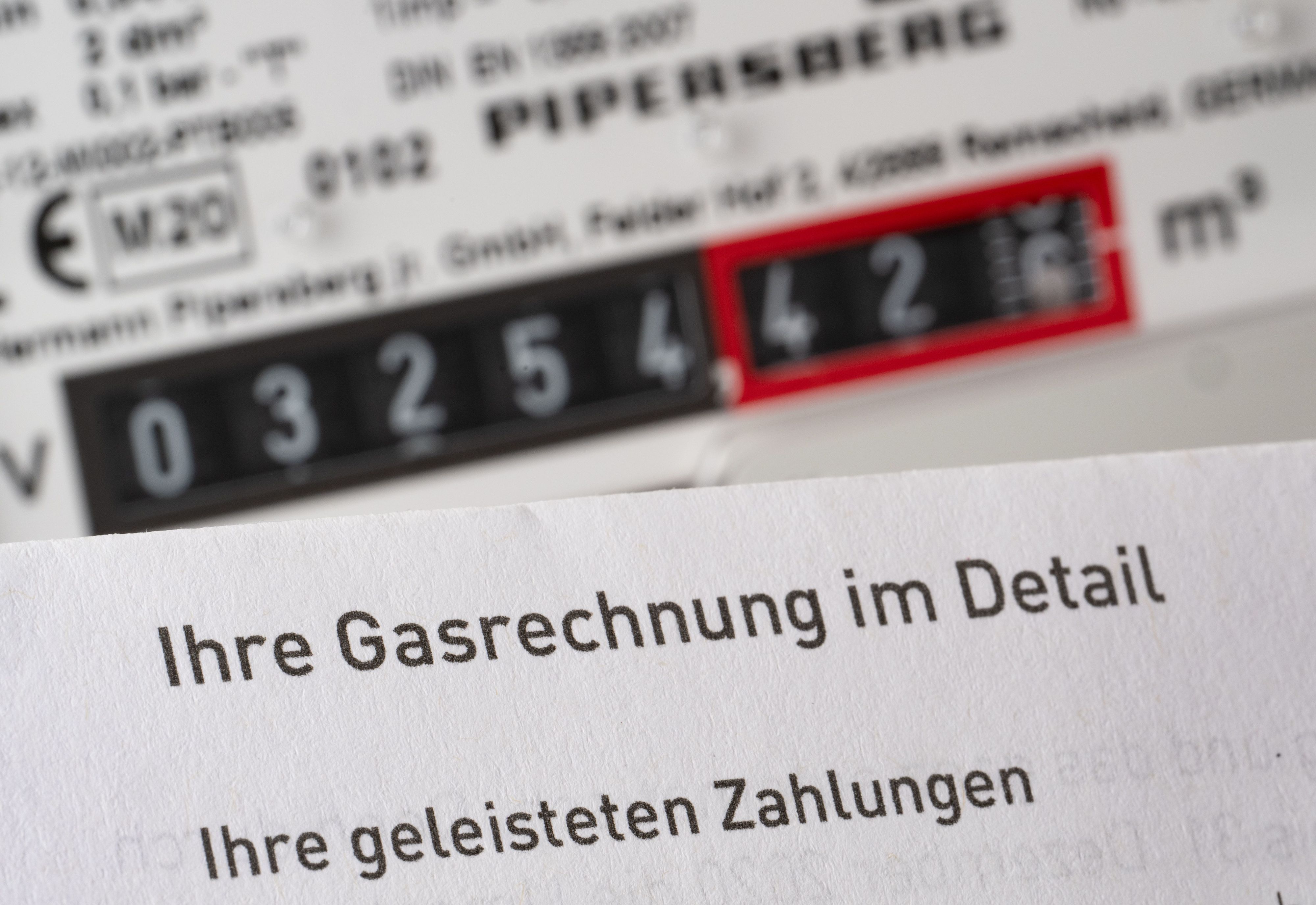 Eine Gasrechnung wird in einem privaten Haushalt vor einem Gaszähler gehalten (Symbolbild).