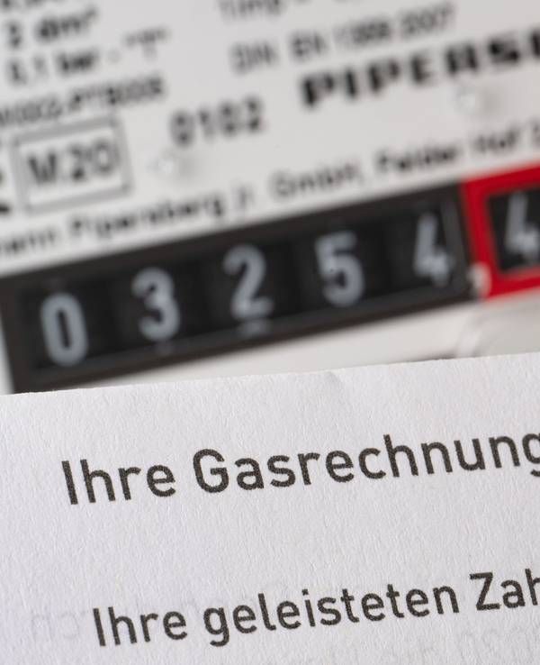 Eine Gasrechnung wird in einem privaten Haushalt vor einem Gaszähler gehalten (Symbolbild).