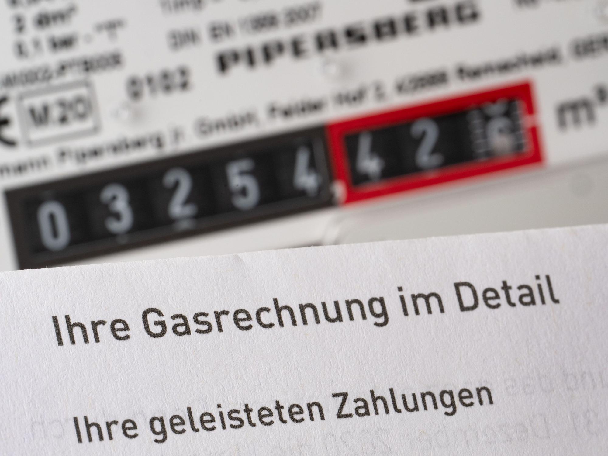 Eine Gasrechnung wird in einem privaten Haushalt vor einem Gaszähler gehalten (Symbolbild).