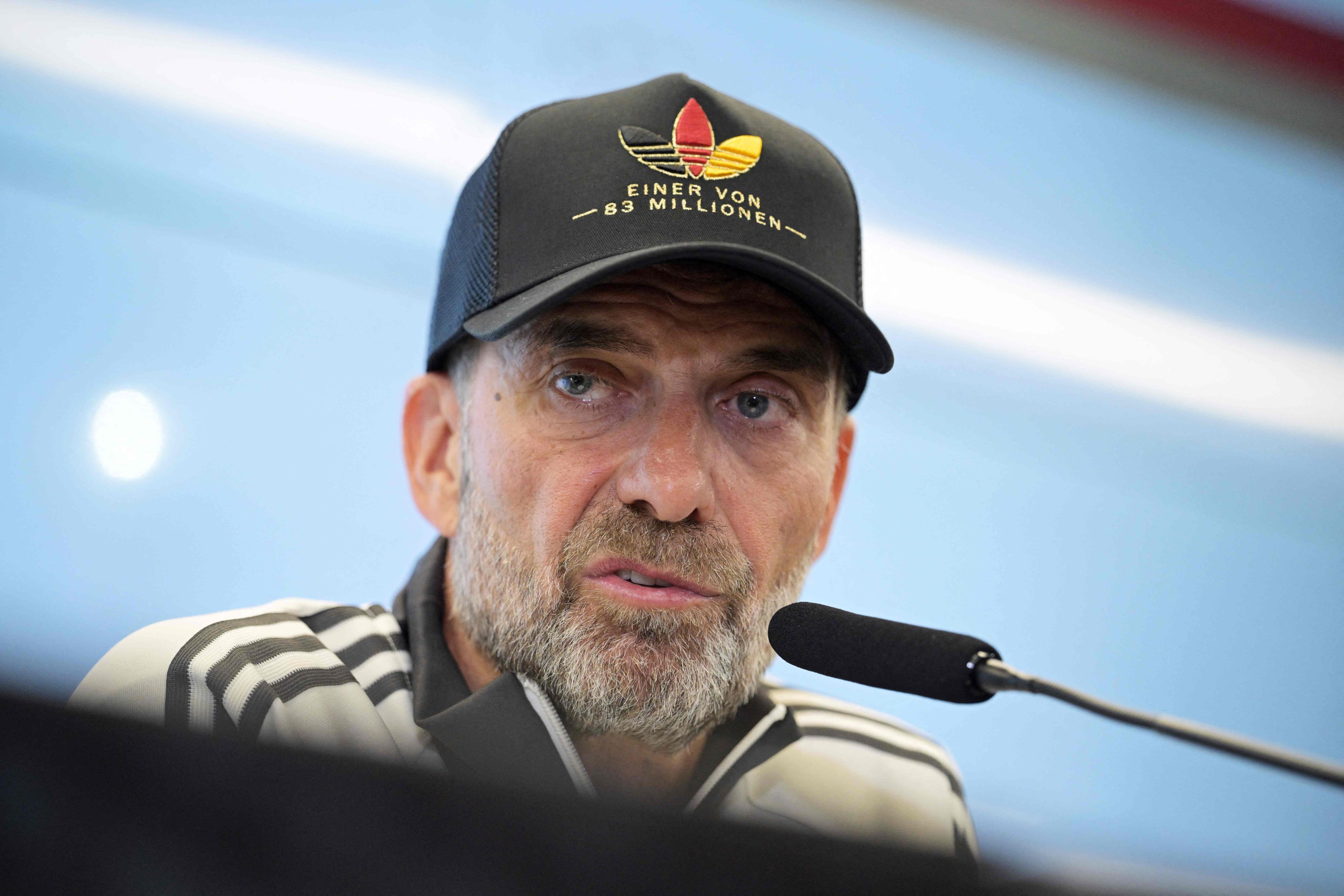 Jürgen Klopp mit Adidas-Deutschland-Mütze auf einer Pressekonferenz.
