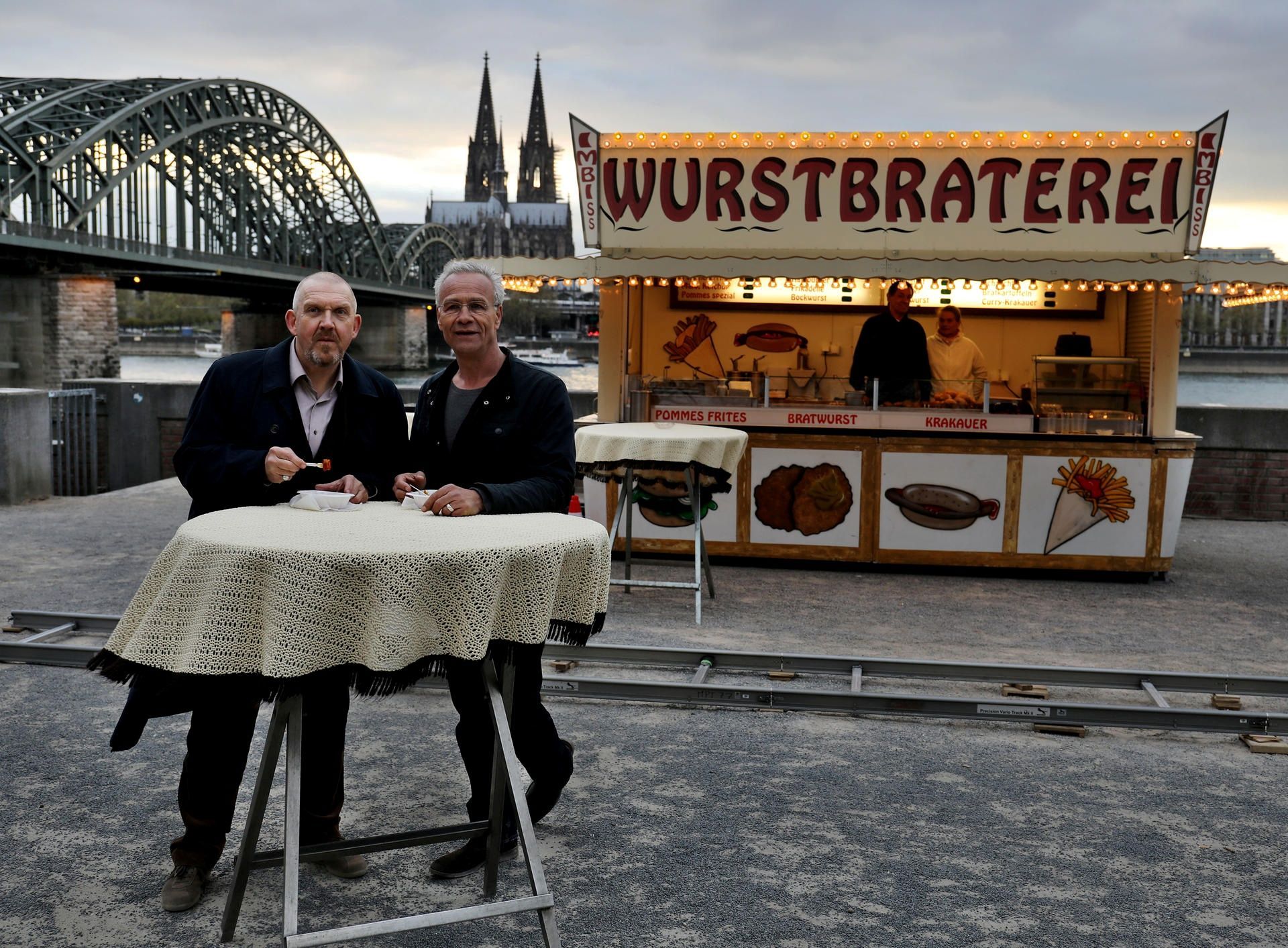Die Tatort-Kommissare Freddy Schenk (Dietmar Bär, l.) und Max Ballauf (Klaus J. Behrendt) an der legendären Currywurst-Bude.