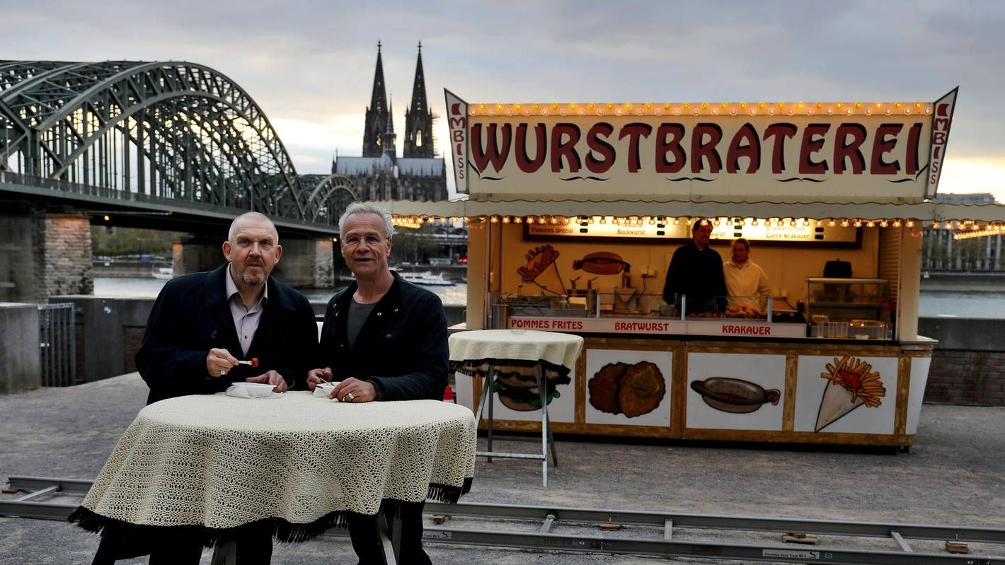 Die Tatort-Kommissare Freddy Schenk (Dietmar Bär, l.) und Max Ballauf (Klaus J. Behrendt) an der legendären Currywurst-Bude.