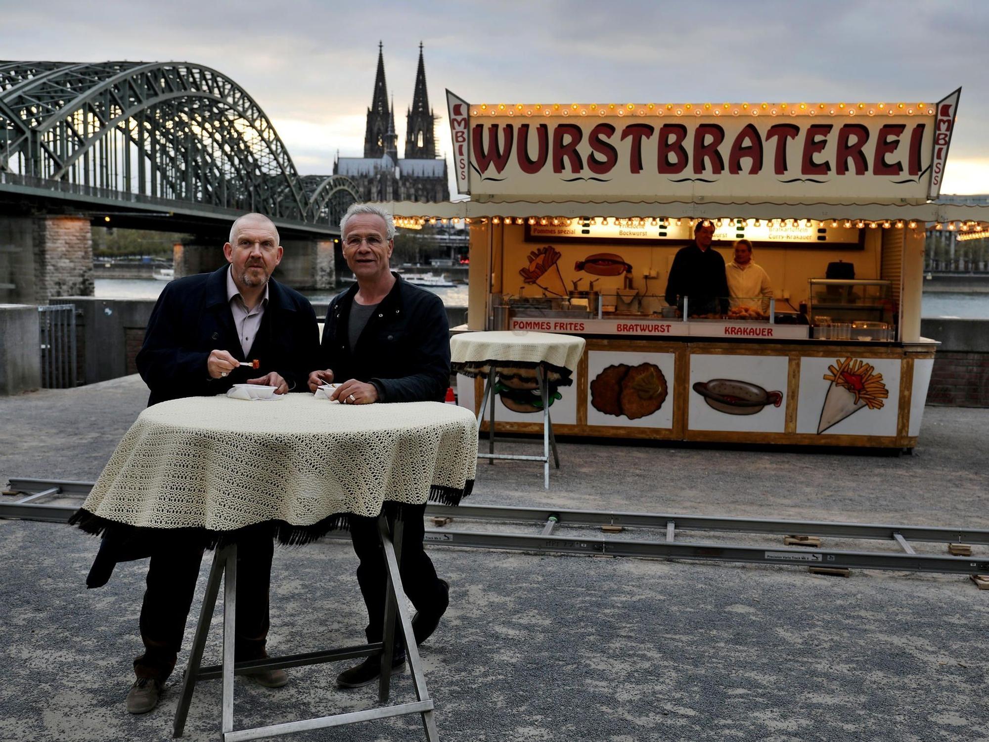 Die Tatort-Kommissare Freddy Schenk (Dietmar Bär, l.) und Max Ballauf (Klaus J. Behrendt) an der legendären Currywurst-Bude.