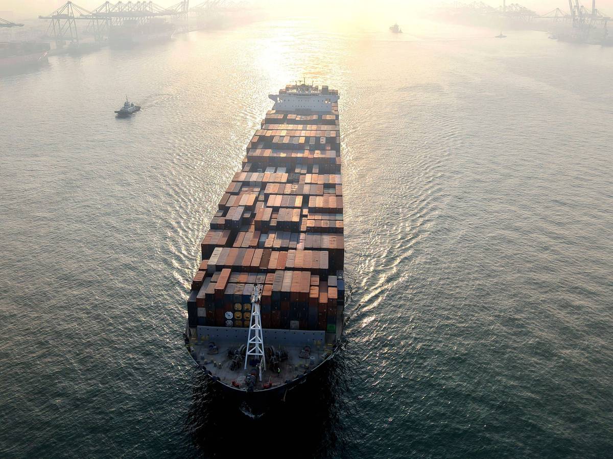 Ein Containerschiff fährt in einen Hafen.