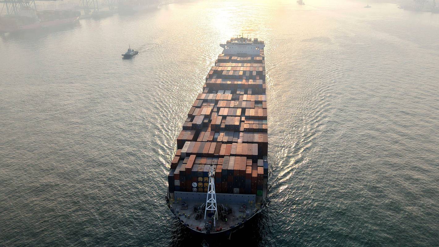 Ein Containerschiff fährt in einen Hafen.