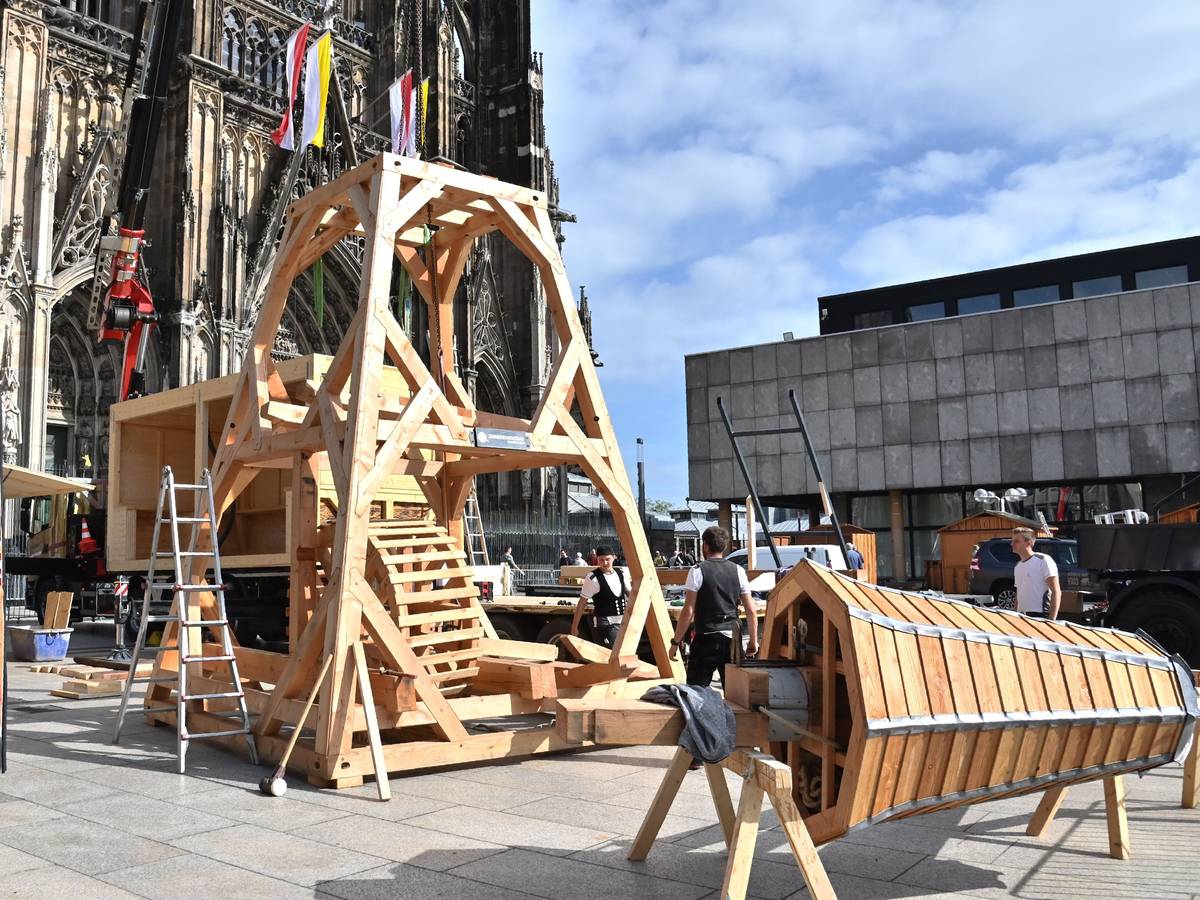 Ein Teil eines hölzernen Krans steht vor dem Kölner Dom, die Spitze liegt noch daneben.