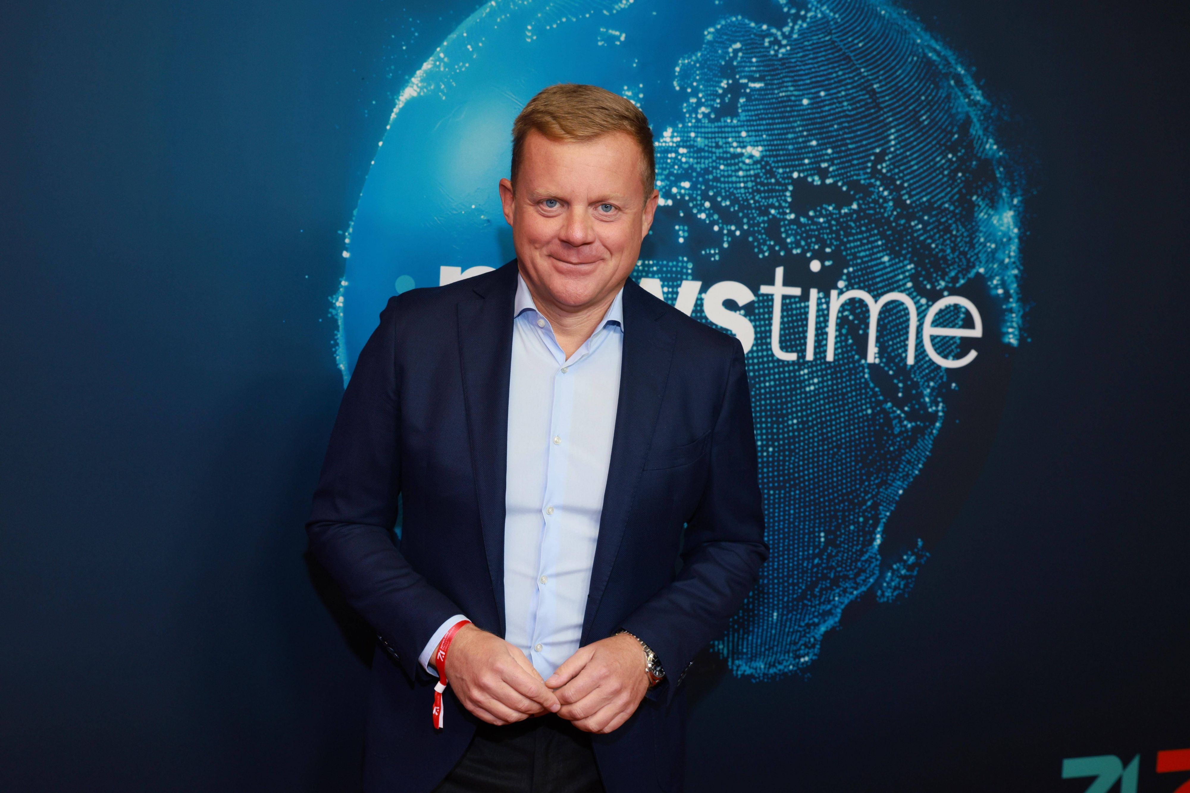 Marc Bator lächelt vor Newstime-Hintergrund