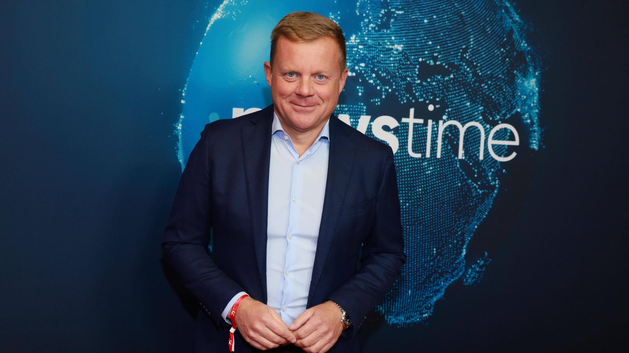 Marc Bator lächelt vor Newstime-Hintergrund