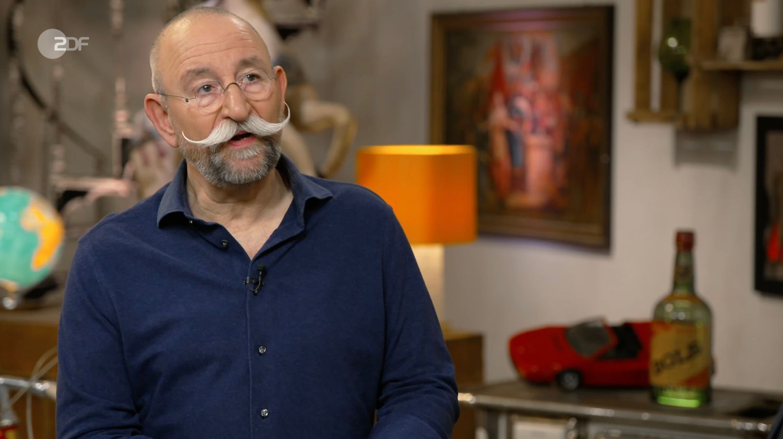 „Eines der hübschesten Schilder, das ich je gesehen habe“, schwärmte Lichter, stutzte jedoch über die Schrauben an den Ecken. Von Emailleschildern kannte er diese nicht. Experte Detlev Kümmel klärte ihn auf: Das Werbeschild war mit einem Hinterglasdruck gefertigt. „Ach, das ist Glas?“, wunderte sich Lichter. (Bild: ZDF)