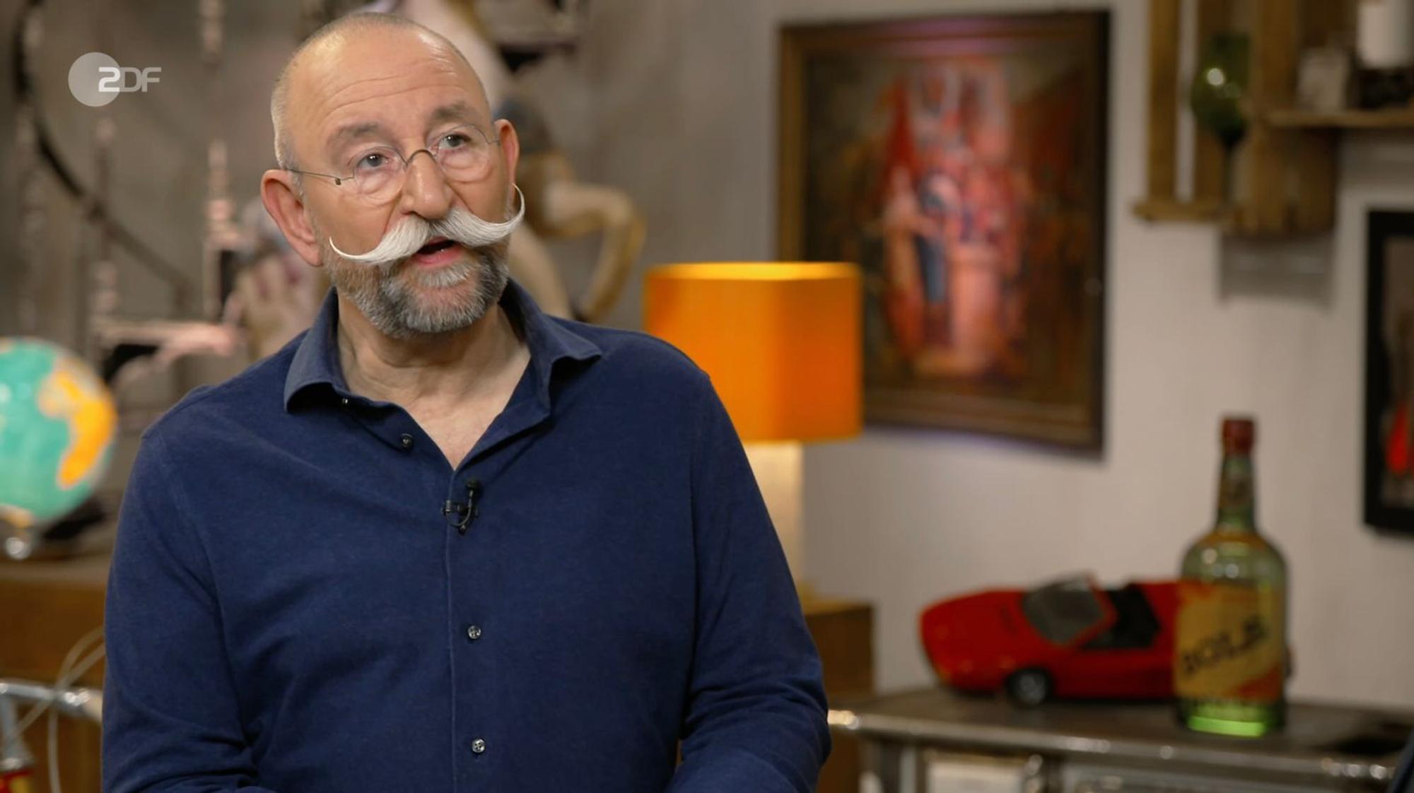 „Eines der hübschesten Schilder, das ich je gesehen habe“, schwärmte Lichter, stutzte jedoch über die Schrauben an den Ecken. Von Emailleschildern kannte er diese nicht. Experte Detlev Kümmel klärte ihn auf: Das Werbeschild war mit einem Hinterglasdruck gefertigt. „Ach, das ist Glas?“, wunderte sich Lichter. (Bild: ZDF)