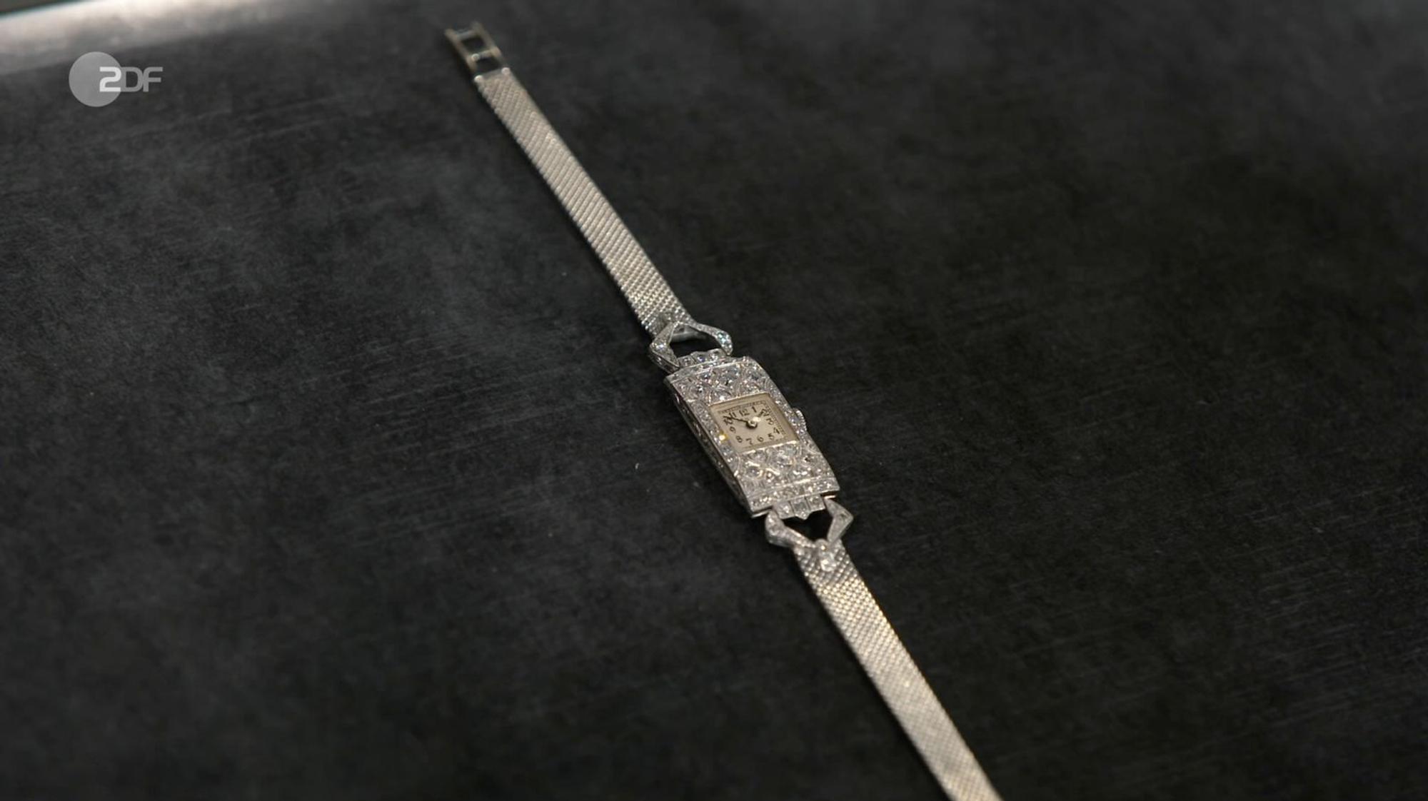 Als weiteres Objekt der Sendung wurde eine Schmuck-Uhr von Heide Rezepa-Zabel auf die 1930er-Jahre datiert. Die Art-déco-Uhr von die Zenith war aus 750er Weißgold und Platin mit 64 Diamanten gefertigt. Gewünscht wurden 2.000 Euro, geschätzt 2.900 bis 3.000 Euro und von Susanne Steiger schließlich 2.850 Euro gezahlt. (Bild: ZDF)
