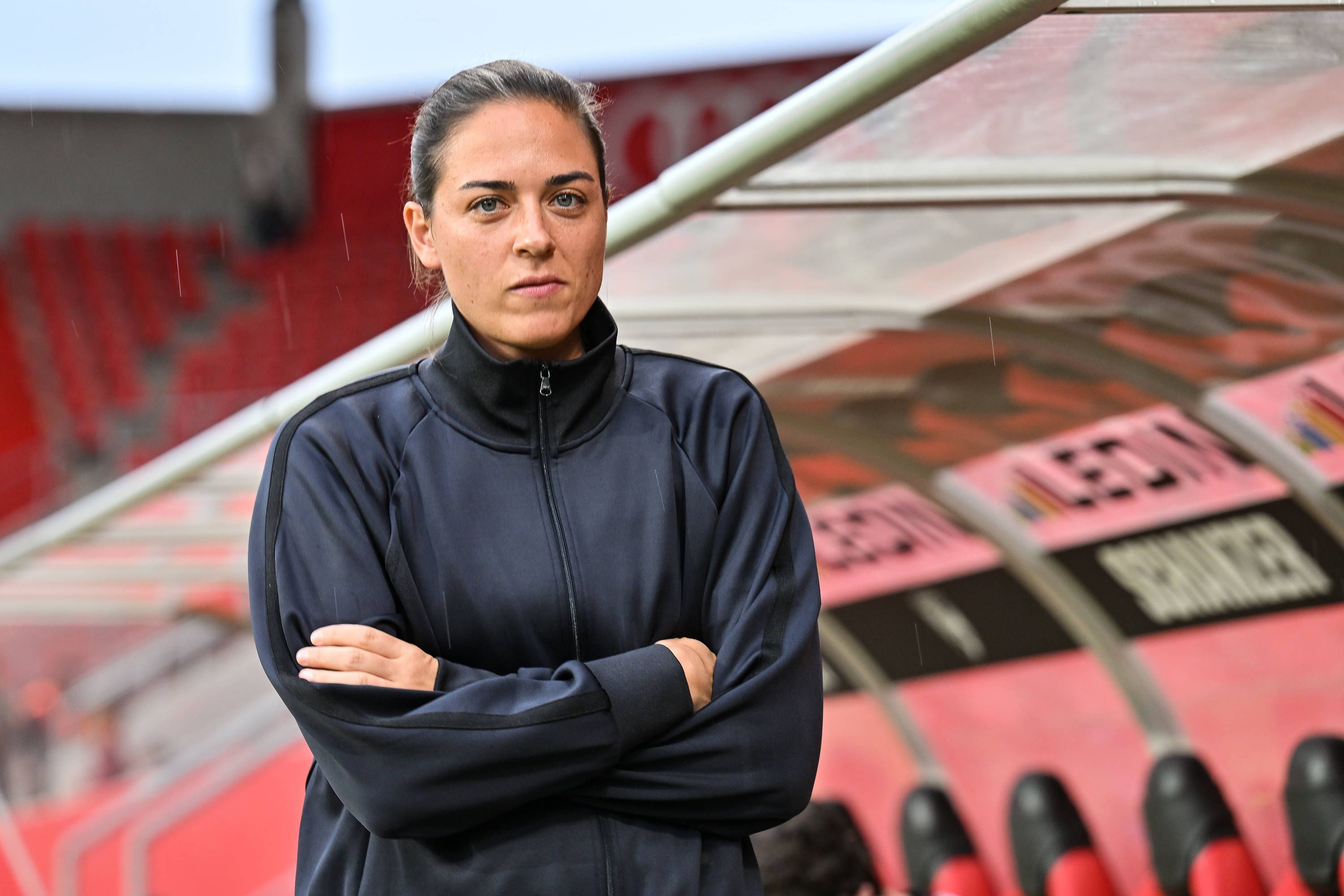 Sabrina Wittmann mit verschränkten Armen vor der Trainerbank.