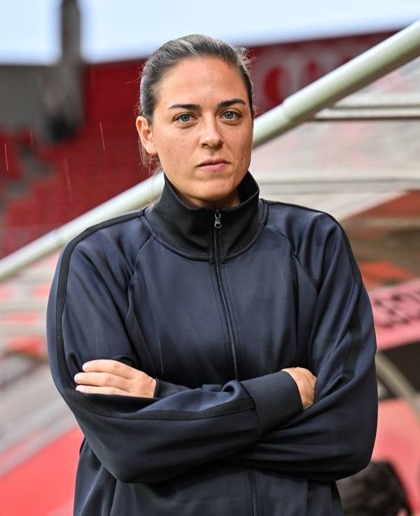 Sabrina Wittmann mit verschränkten Armen vor der Trainerbank.