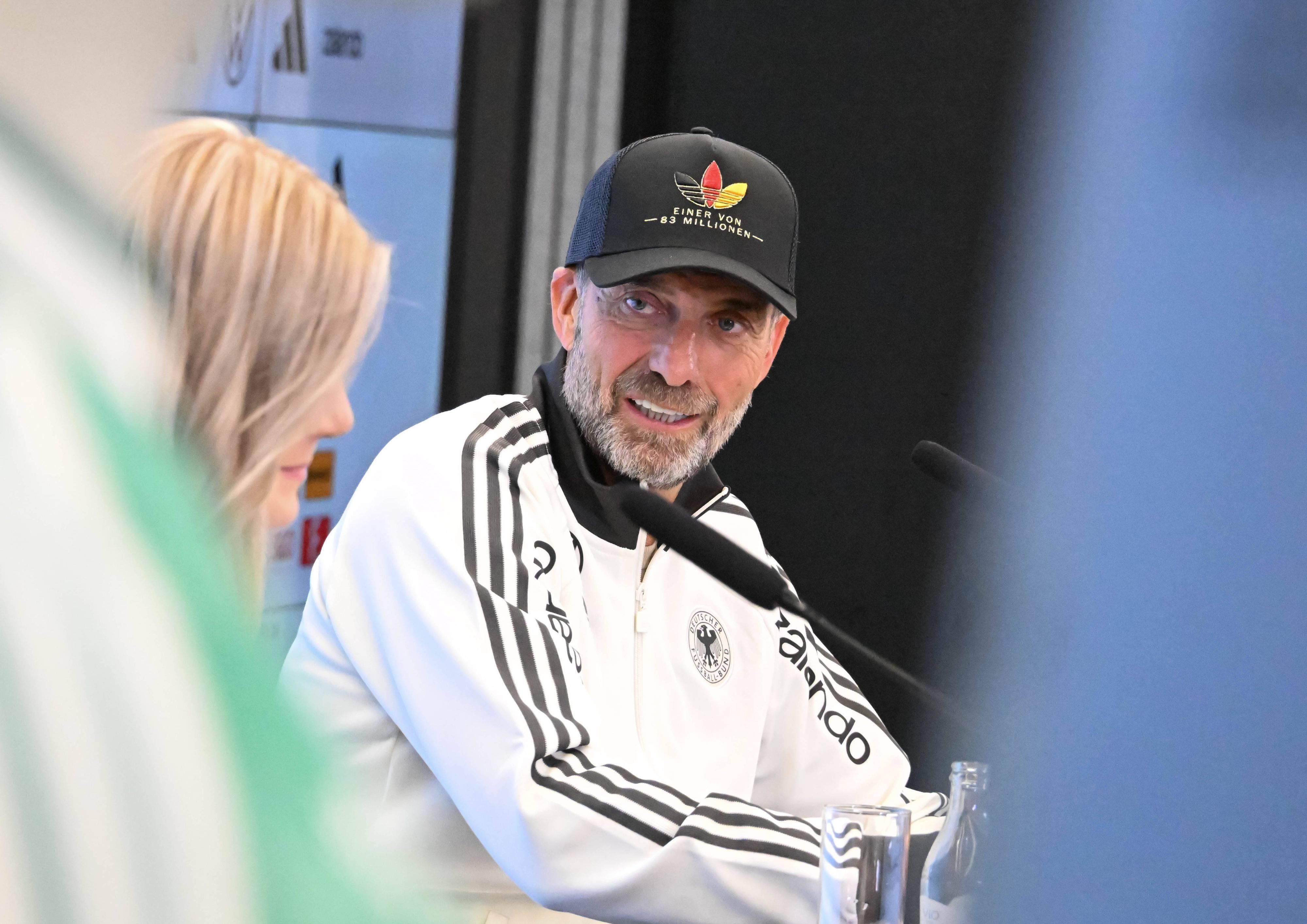Jürgen Klopp guckt bei einer Pressekonferenz zur DFB-Pressesprecherin.