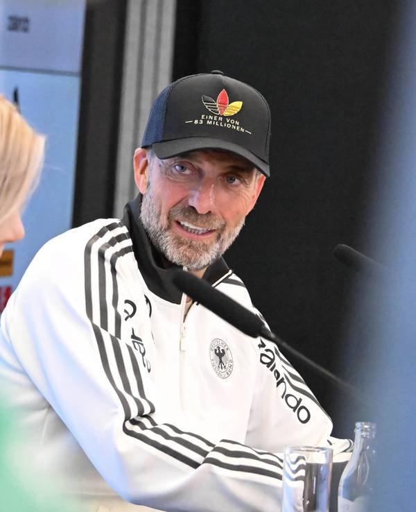 Jürgen Klopp guckt bei einer Pressekonferenz zur DFB-Pressesprecherin.