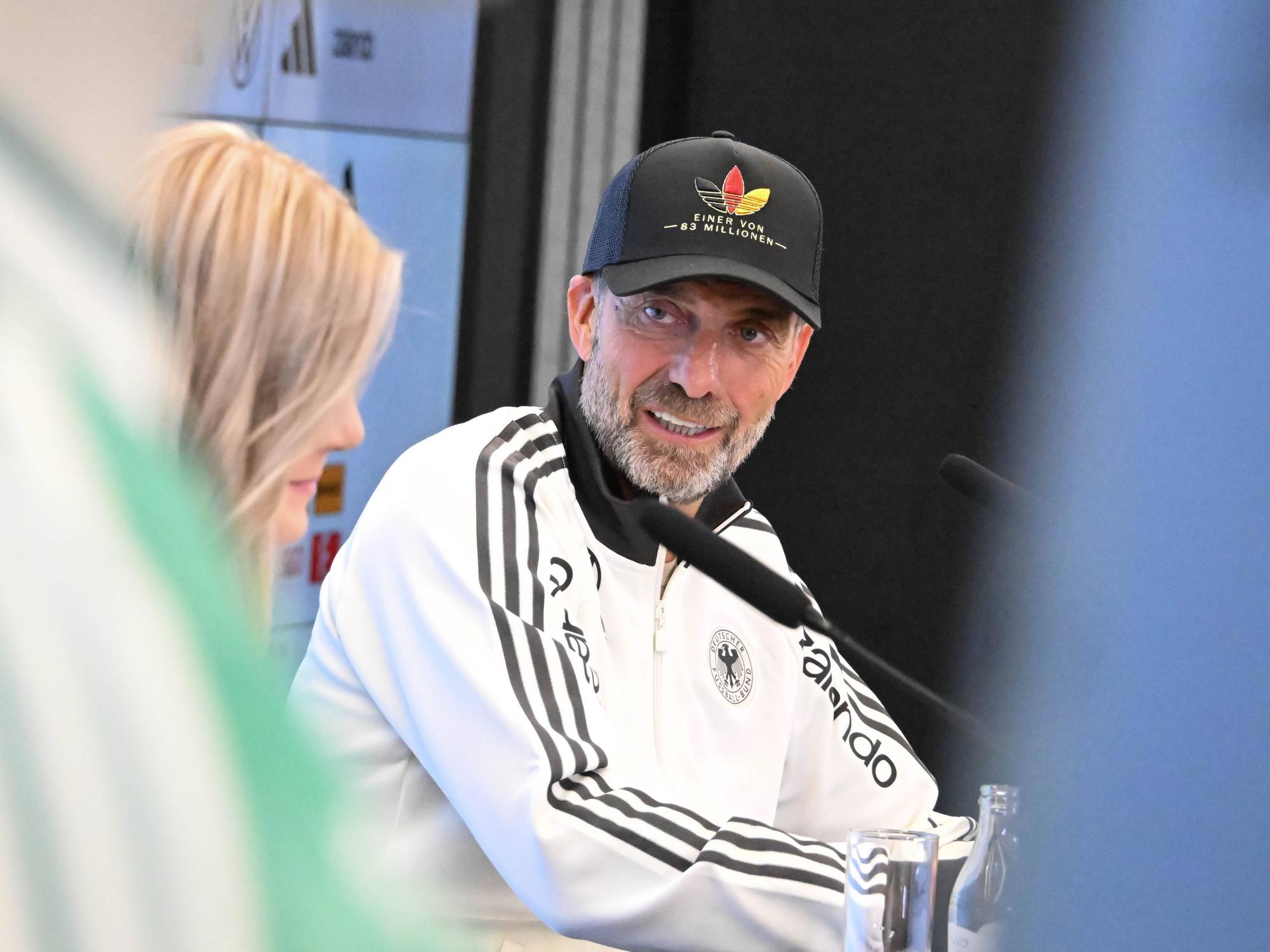 Jürgen Klopp guckt bei einer Pressekonferenz zur DFB-Pressesprecherin.