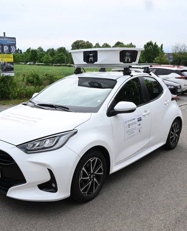 Ein Scan-Auto, das automatisch Parksünder registriert, fährt an geparkten Fahrzeugen vorbei.