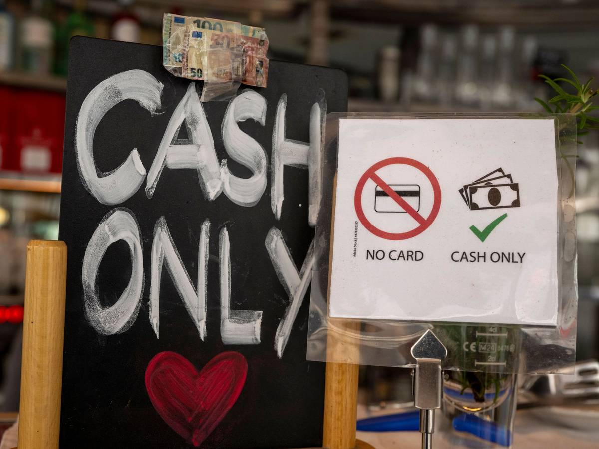Ein Schild mit der Aufschrift „No Card – Cash Only“ steht in einem Café.