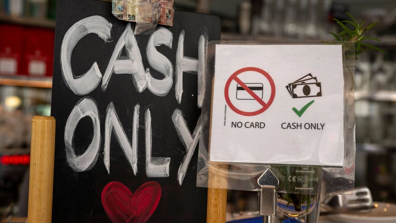 Ein Schild mit der Aufschrift „No Card – Cash Only“ steht in einem Café.