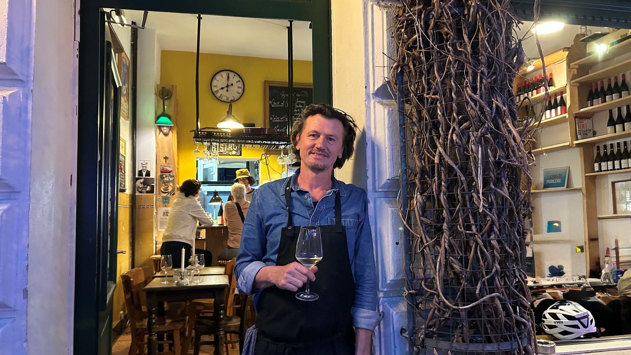 David Boucherie steht mit einem Glas Wein in der Tür seines Lokals.