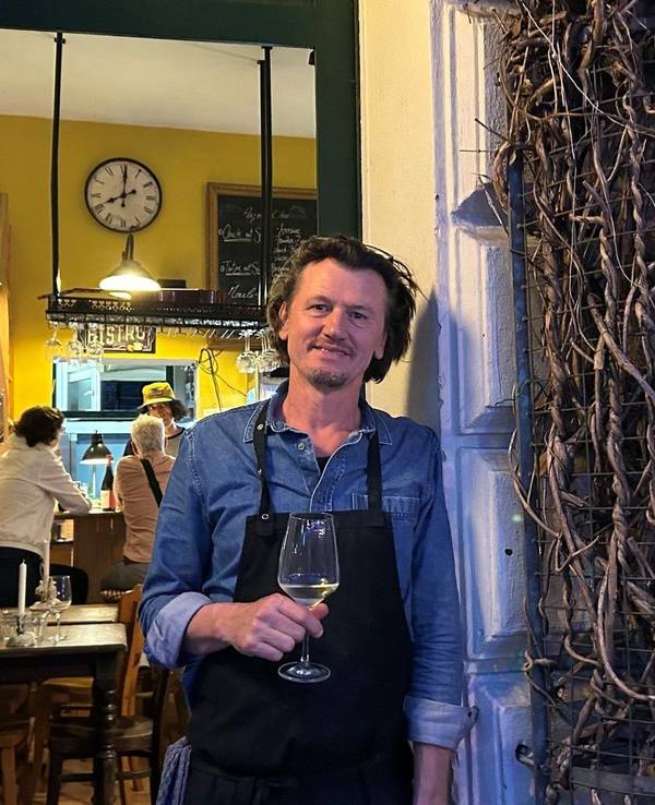 David Boucherie steht mit einem Glas Wein in der Tür seines Lokals.