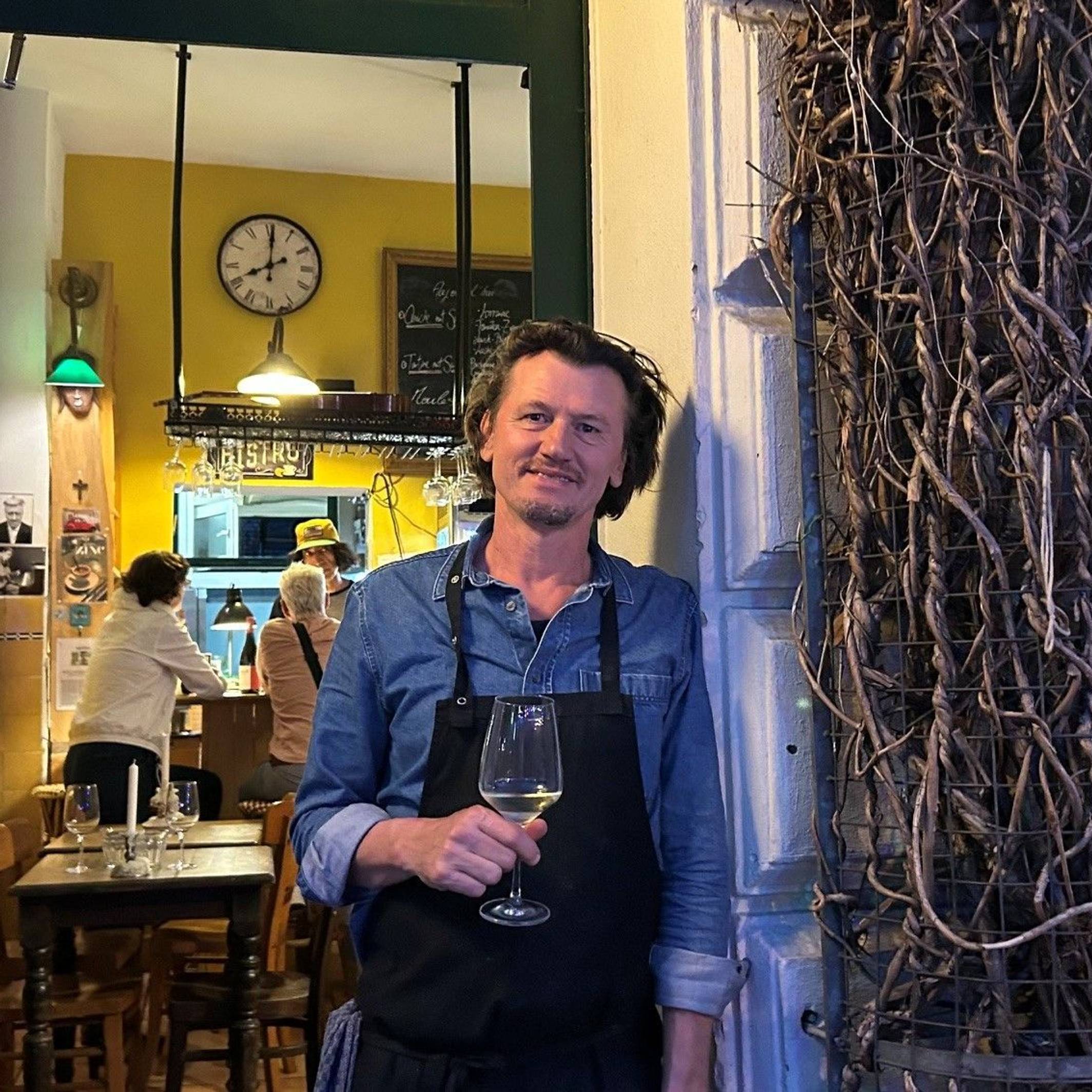 David Boucherie steht mit einem Glas Wein in der Tür seines Lokals.