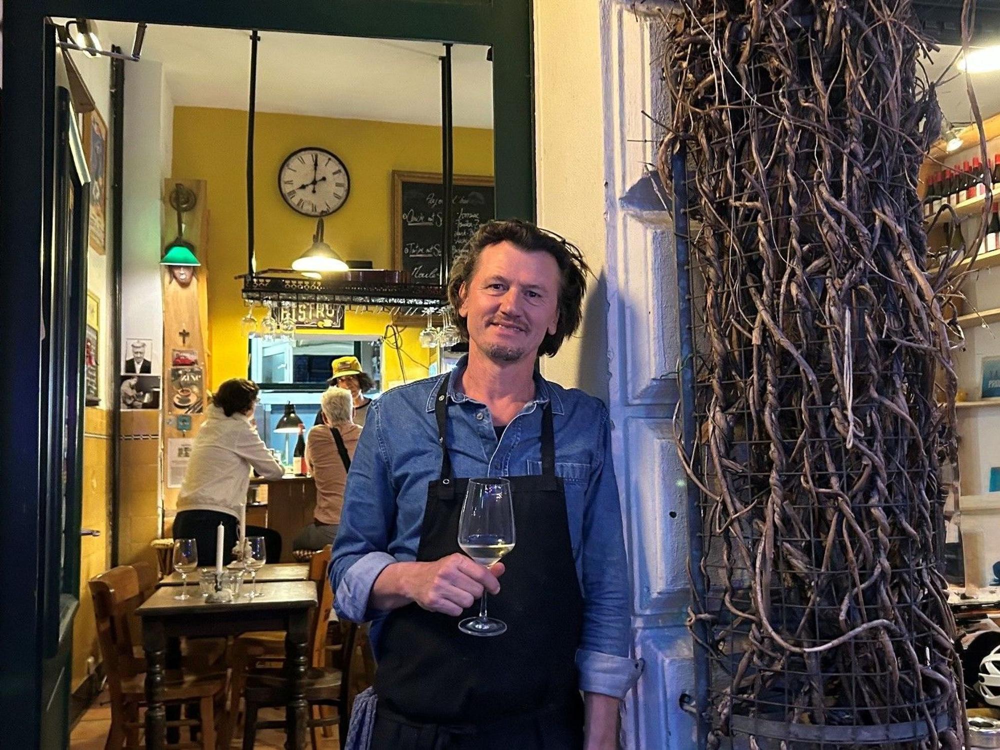 David Boucherie steht mit einem Glas Wein in der Tür seines Lokals.