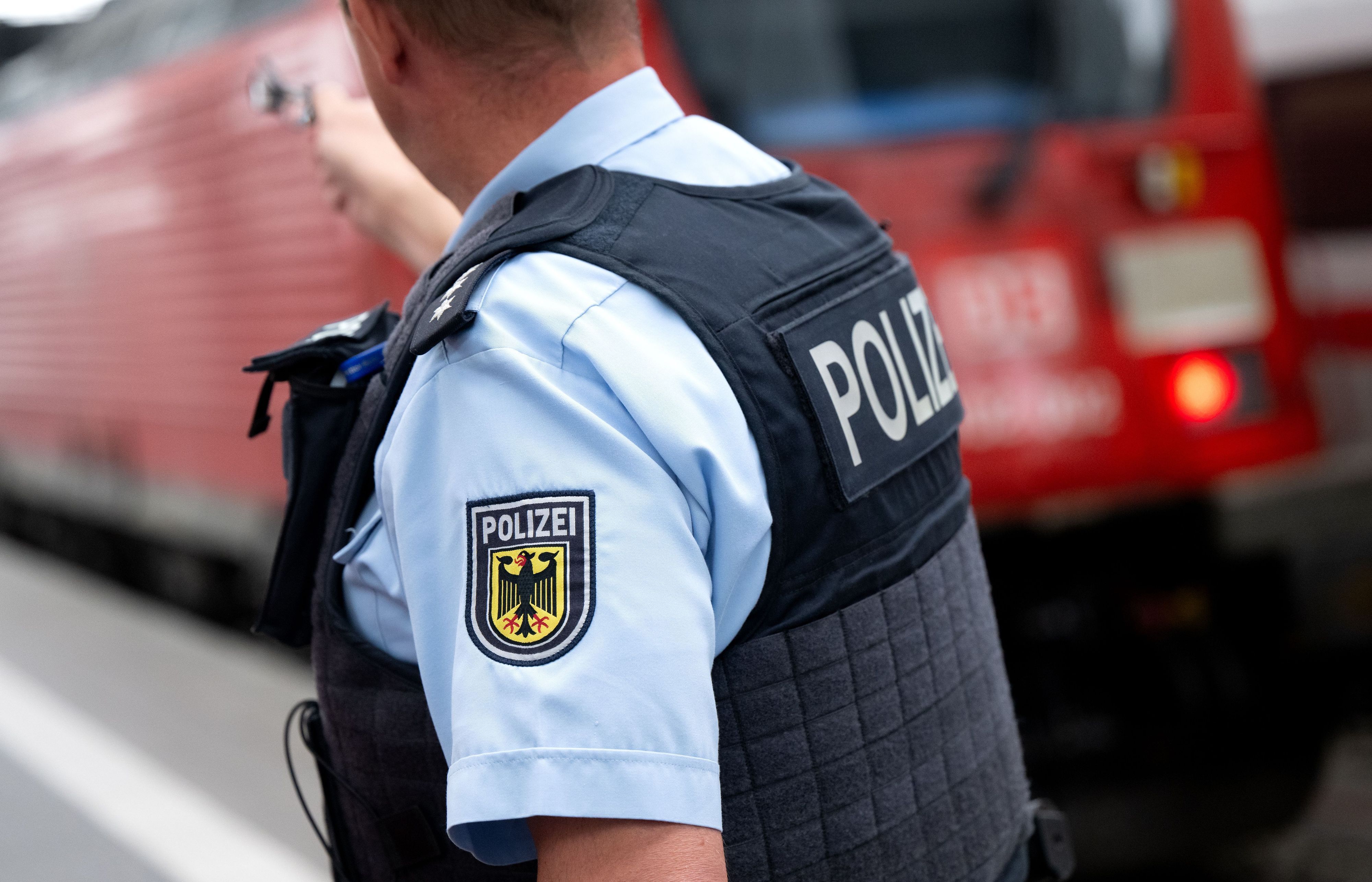 Ein Bundespolizist steht an einem Bahnsteig vor einem Zug der Deutschen Bahn.