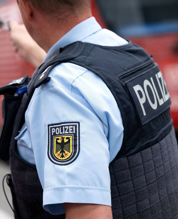 Ein Bundespolizist steht an einem Bahnsteig vor einem Zug der Deutschen Bahn.