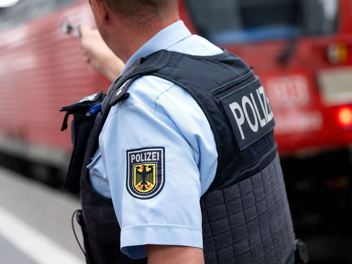 Ein Bundespolizist steht an einem Bahnsteig vor einem Zug der Deutschen Bahn.