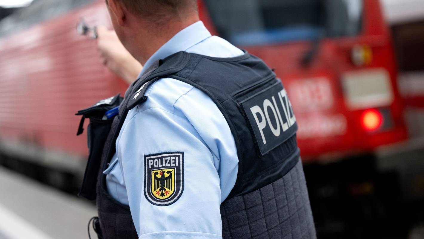 Ein Bundespolizist steht an einem Bahnsteig vor einem Zug der Deutschen Bahn.