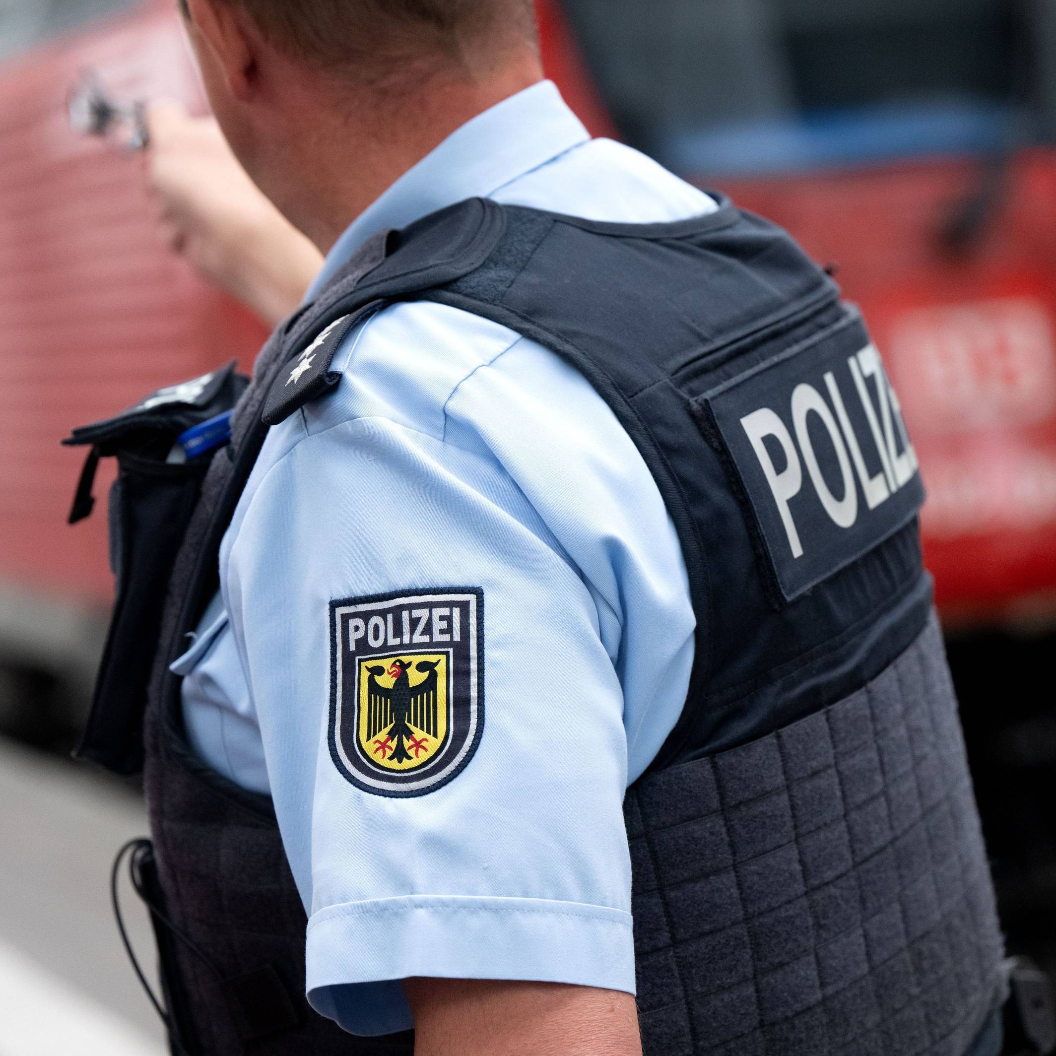 Ein Bundespolizist steht an einem Bahnsteig vor einem Zug der Deutschen Bahn.