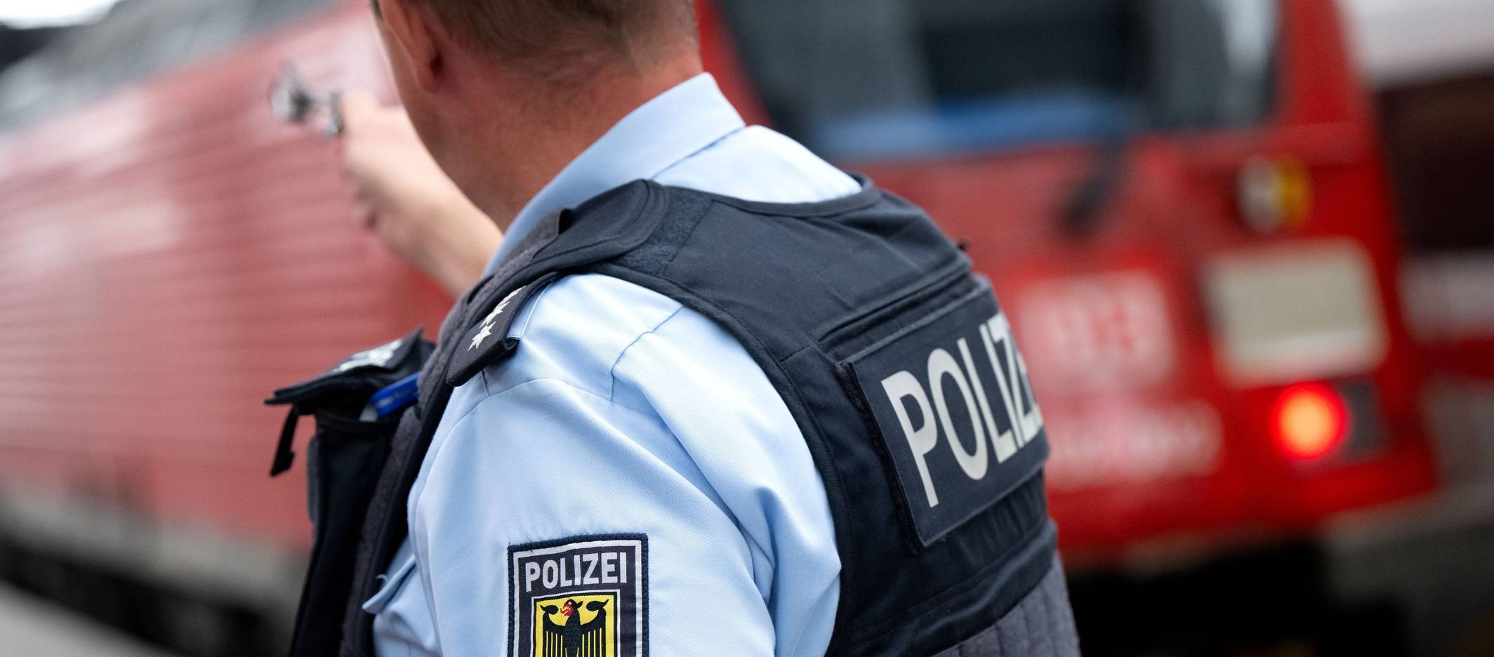 Ein Bundespolizist steht an einem Bahnsteig vor einem Zug der Deutschen Bahn.