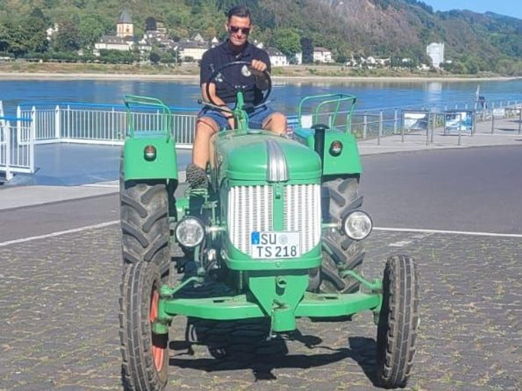 Tobias Schmitz sitzt auf seinem Trecker am Rheinufer.