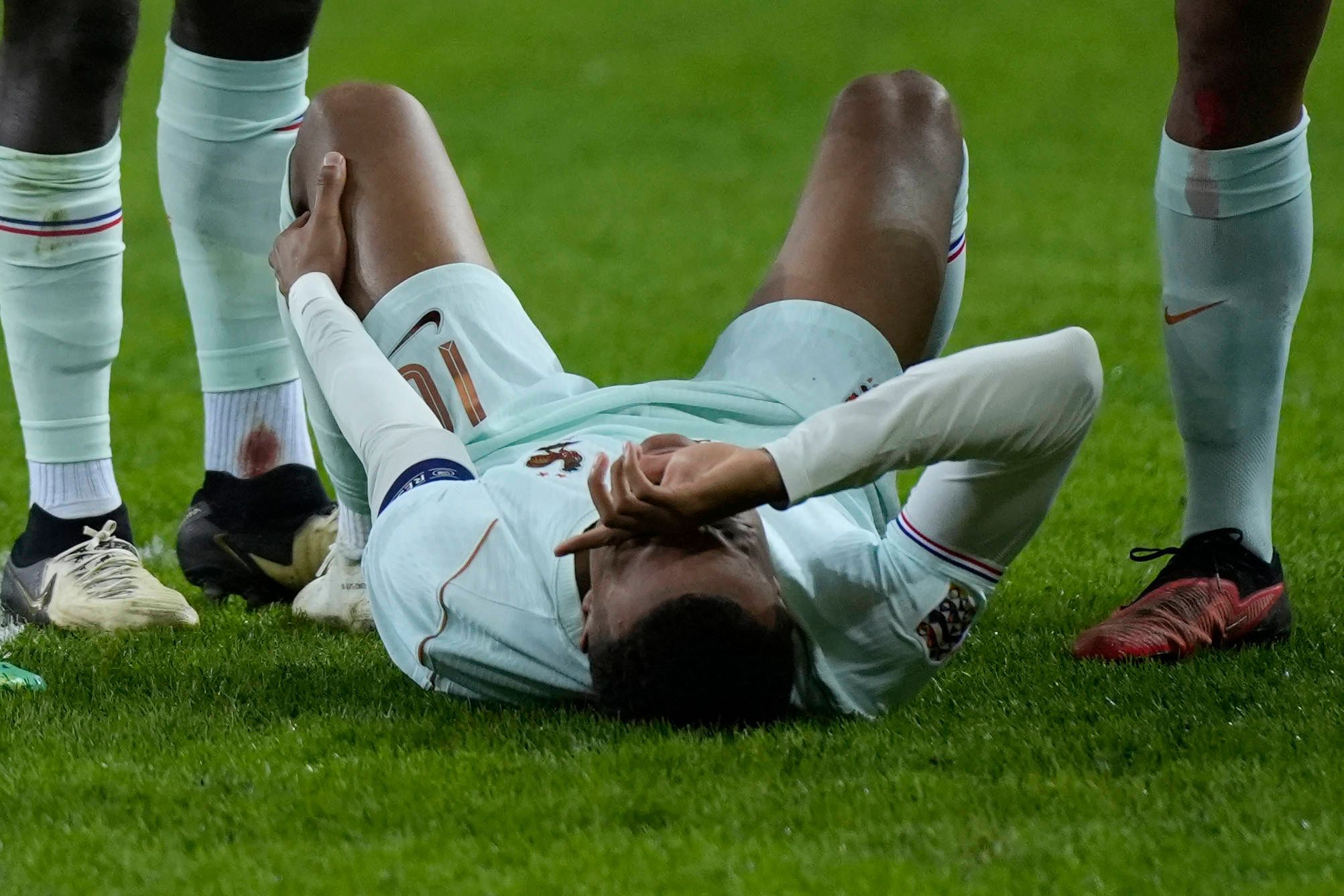 Kylian Mbappé liegt auf dem Boden und hält sich das linke Knie.