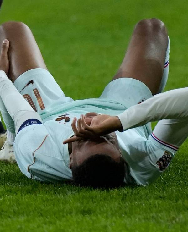 Kylian Mbappé liegt auf dem Boden und hält sich das linke Knie.