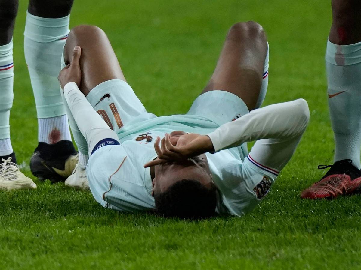 Kylian Mbappé liegt auf dem Boden und hält sich das linke Knie.