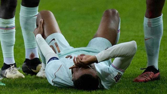 Kylian Mbappé liegt auf dem Boden und hält sich das linke Knie.