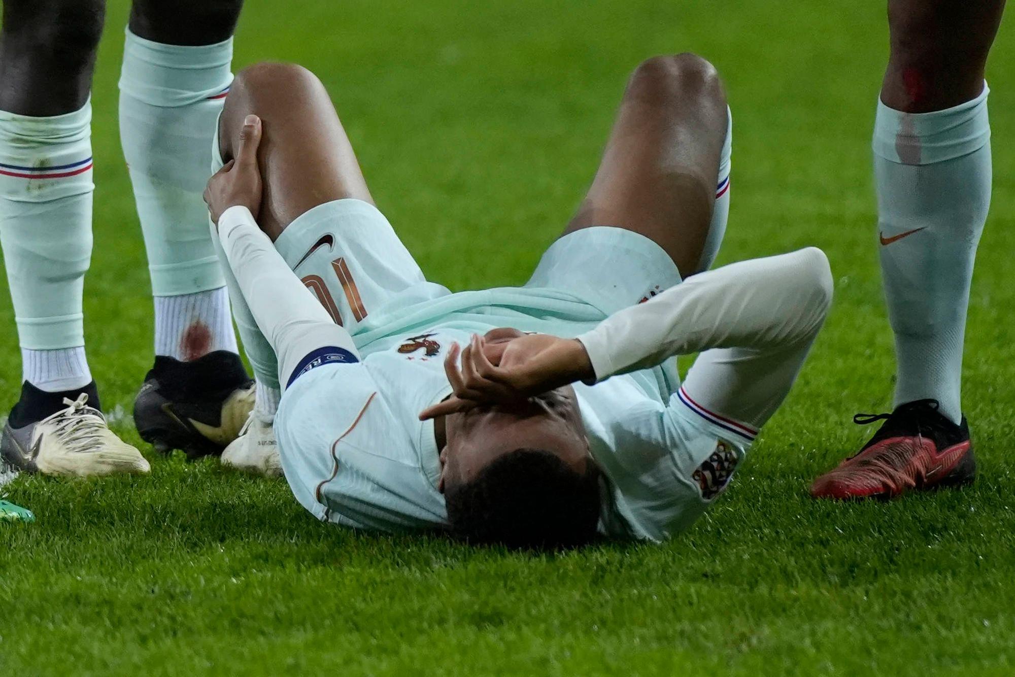 Kylian Mbappé liegt auf dem Boden und hält sich das linke Knie.