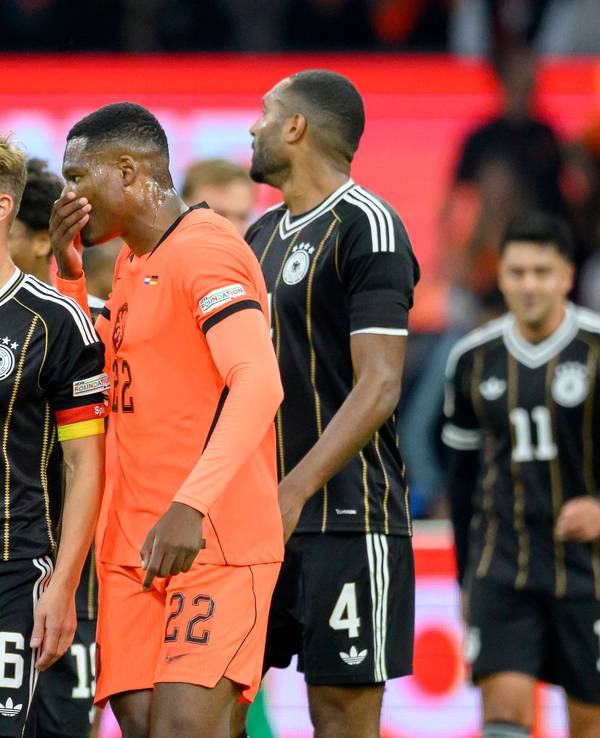 Denzel Dumfries sagt etwas zu Joshua Kimmich und hält dabei die Hand vors Gesicht.