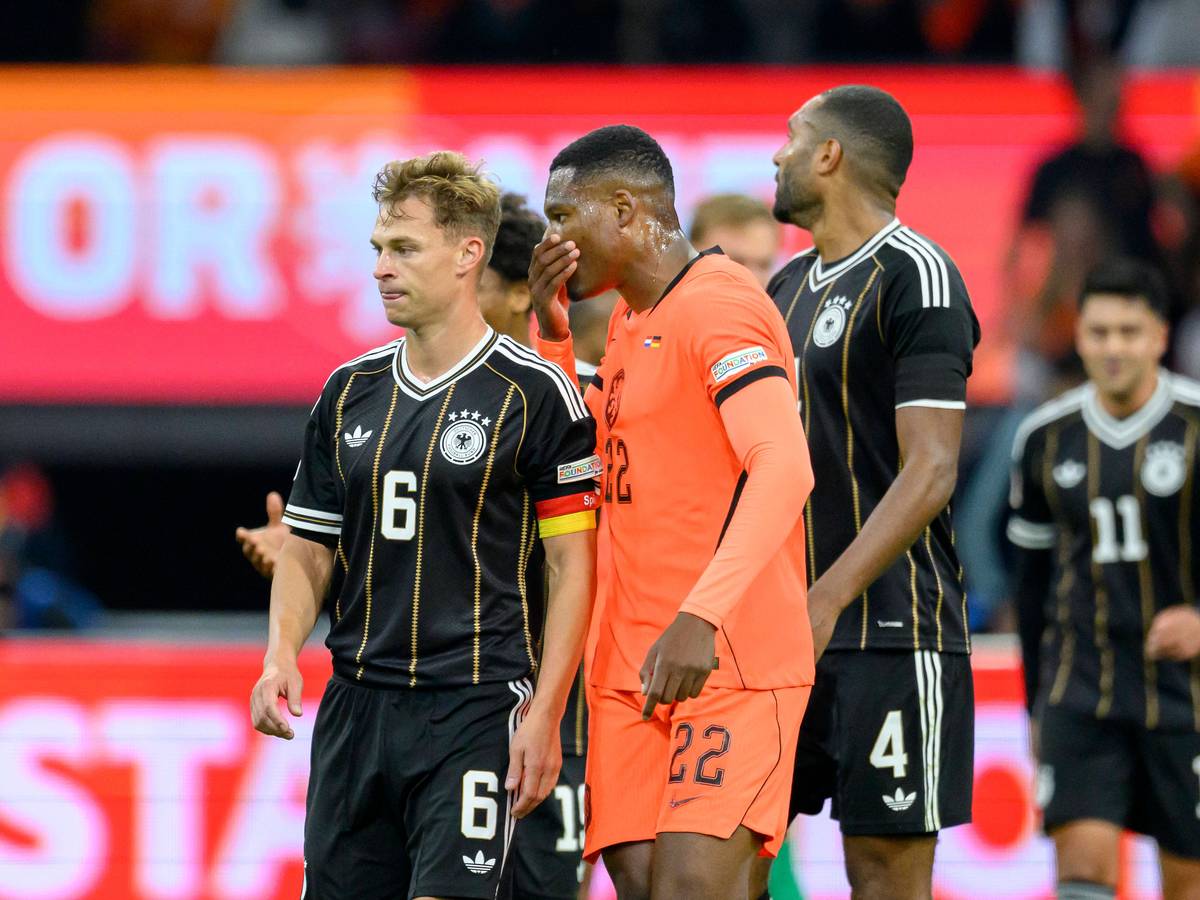 Denzel Dumfries sagt etwas zu Joshua Kimmich und hält dabei die Hand vors Gesicht.